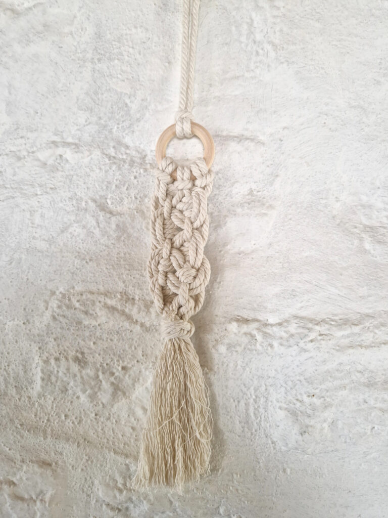 Petite décoration artisanale en macramé toute au naturel, avec des nœuds complexes et anneau de bois.